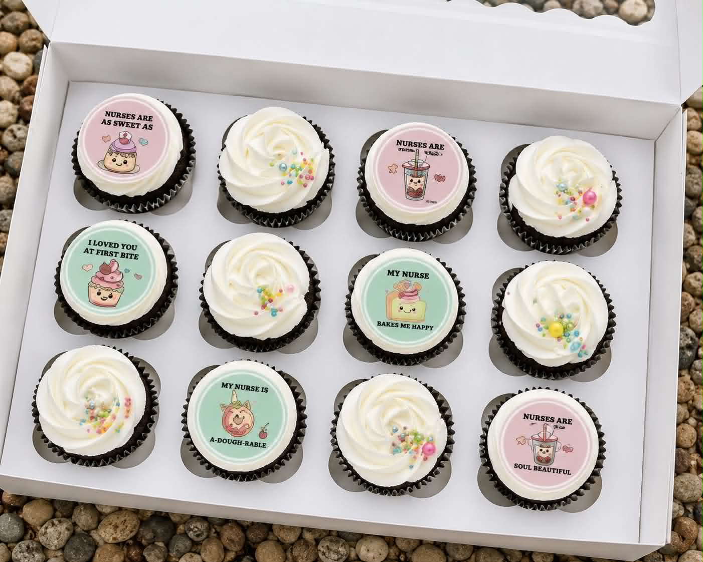 Box of 12 chocolate cupcakes with white swirl buttercream and pastel nurse-themed edible print toppers reading Nurses Are As Sweet As, My Nurse Bakes Me Happy and A-Dough-Rable